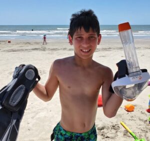 A boy holding an OceanReef Aria full-face snorkel mask.